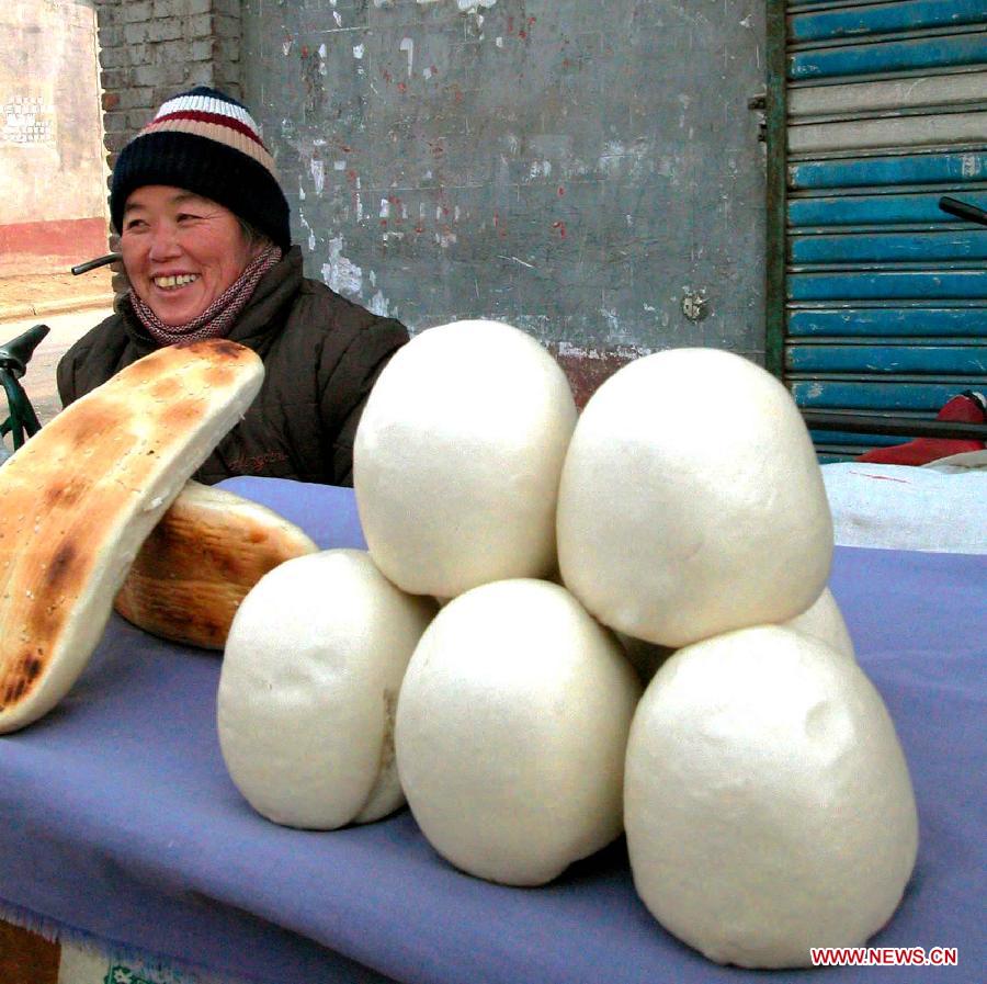 A vendor sells a traditional Spring Festival food, namely "thick stick bun of eastern Henan "on a street in Shangqiu City, central China's Henan Province, Jan. 12, 2003. Chinese people who live in the central China region have formed various traditions to celebrate the Chinese Lunar New Year. (Xinhua/Wang Song)