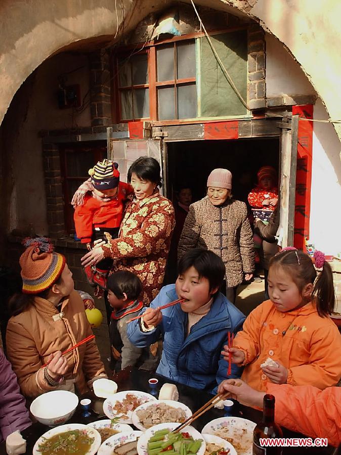 A family gather to have a family-reunion dinner outside their cave dwelling in Qucun Village of Shaanxian County, central China's Henan Province, Feb. 1, 2003. Different from the other parts of China in which people have family reunion dinner on the Chinese New Year's eve, people living in the central China region have the family banquet at the noon of the first day of the lunar month. Chinese people who live in the central China region have formed various traditions to celebrate the Chinese Lunar New Year. (Xinhua/Wang Song)