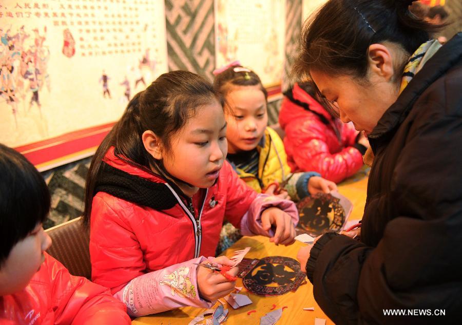 A citizen learns to paper-cuttings at the Hebei Folk Arts Museum in Shijiazhuang, capital of north China's Hebei Province, Feb. 3, 2013. Pupils of Weitong Primary School were invited on Feb. 3 to present paper-cuttings at the museum to greet the upcoming Spring Festival, which falls on Feb. 10 this year. (Xinhua/Zhu Xudong)