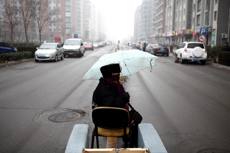 A traffic coordinator sits on a road in Beijing, Jan. 31, 2013. Light snow hit parts of the city on Thursday and the local meteorological observatory issued a yellow alert for icy road. (Xinhua/Jin Liwang)