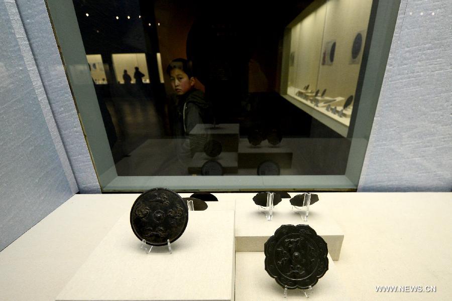 A little child watches bronze mirrors during an ancient bronze mirror exhibition in Hefei, capital of east China's Anhui Province, Feb. 2, 2013. The exhibition, displaying a total of 153 bronze mirrors, opened here Saturday. (Xinhua/Zhang Duan)