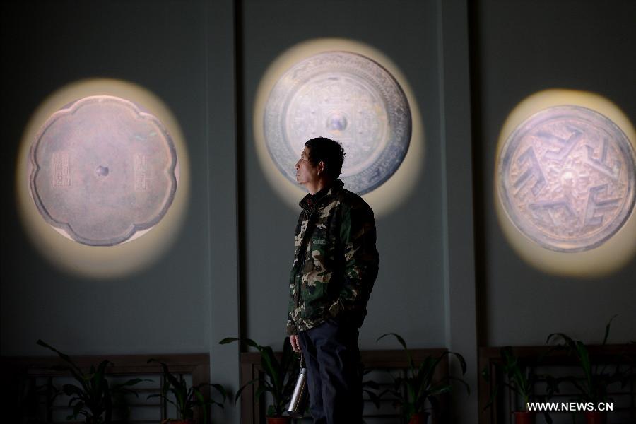 A visitor watches bronze mirrors during an ancient bronze mirror exhibition in Hefei, capital of east China's Anhui Province, Feb. 2, 2013. The exhibition, displaying a total of 153 bronze mirrors, opened here Saturday. (Xinhua/Zhang Duan) 