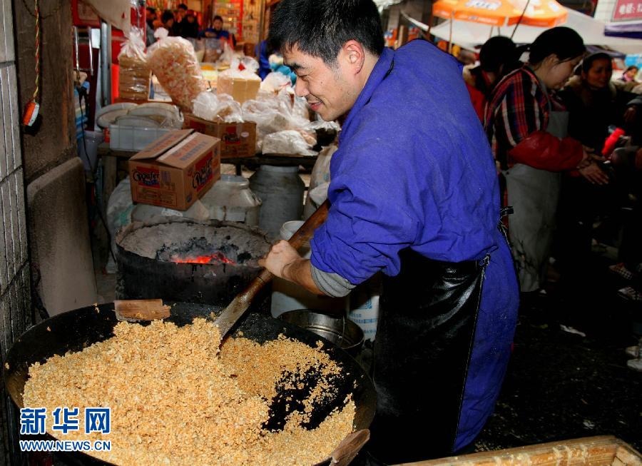 A man stir fries the puffed rice used for making candy bars. It is a tradition to make the snacks with maltose and puffed rice in Jiangxi province on the day of Xiaonian Festival. (Xinhua / XU Zhongting)