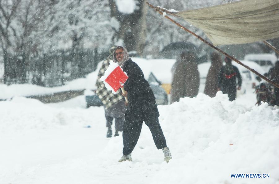 An Afghan man removes snow in front of his shop during heavy snowfall in Kabul, Afghanistan, on Feb. 2, 2013. Over the past two weeks, at least 17 people, 11 of them children, have died because of cold-related diseases in Afghanistan's resettlement areas, according to media reports. (Xinhua/Ahmad Massoud)