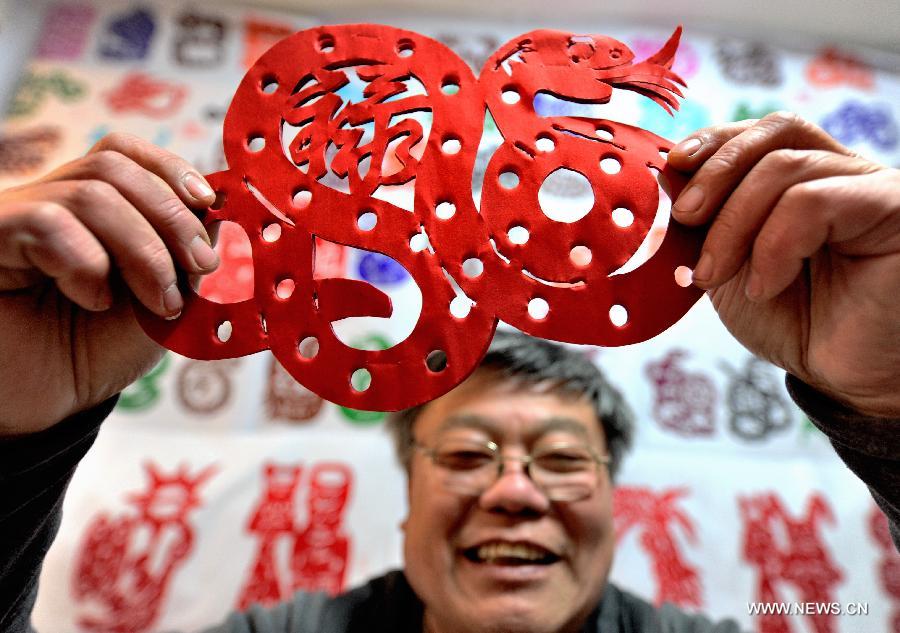 Folk artist Chen Yongnian presents his paper-cut of snake in Xuzhou, east China's Jiangsu Province, Feb. 4, 2013. Chen spent over a month on creating more than 130 pieces of paper-cut artworks of snakes to celebrate the coming Chinese Year of the Snake. (Xinhua/Li Ming)