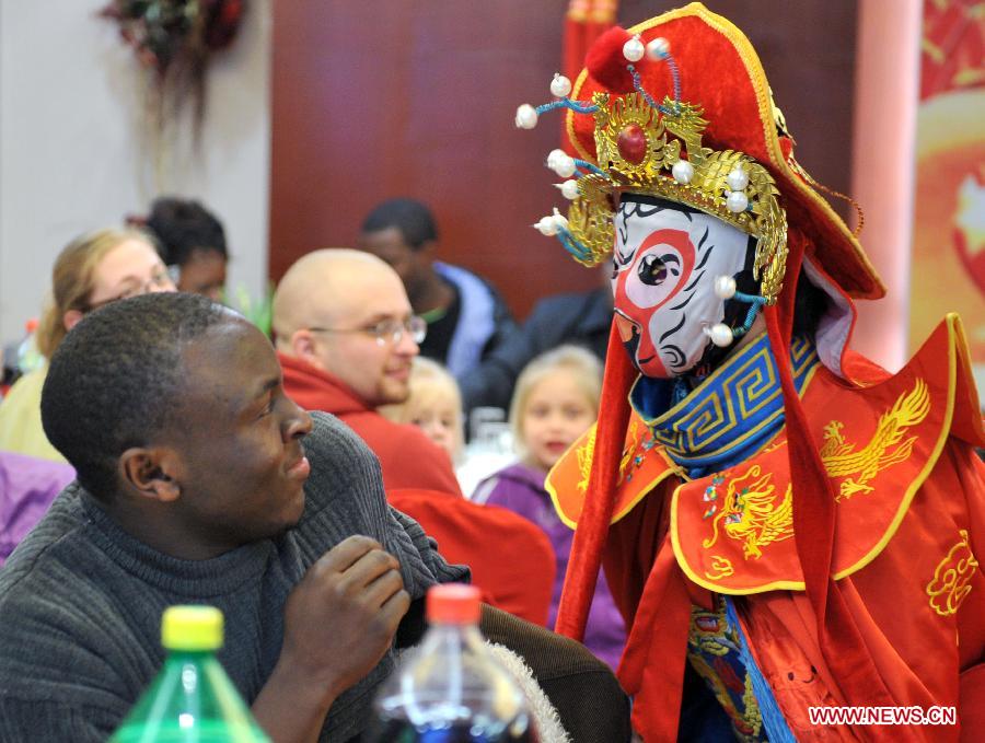 A performer of Sichuan Opera interacts with overseas students in an activity to celebrate the Chinese New Year at the Nanjing Agricultural University in Nanjing, capital of east China's Jiangsu Province, Feb. 4, 2013. More than 50 overseas students from over 20 countries and regions experienced Chinese traditional cultural activities with local students. (Xinhua) 