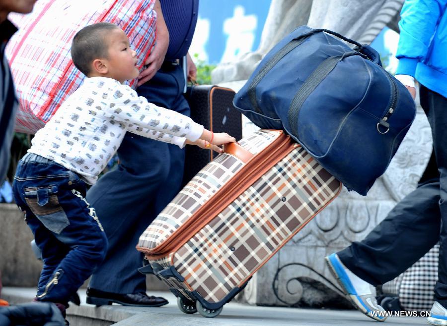 A little boy helps his family push the luggage case at Nanning train station in Nanning, capital of south China's Guangxi Zhuang Autonomous Region, Feb. 3, 2013. Many children travel with their families during the 40-day Spring Festival travel rush which started on Jan. 26. The Spring Festival, which falls on Feb. 10 this year, is traditionally the most important holiday of the Chinese people. Public transportation is expected to accommodate about 3.41 billion trips nationwide during the holiday,including 225 million trips by railways. (Photo/Xinhua)