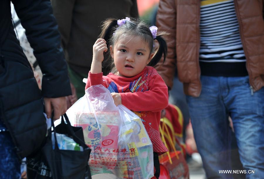 A little girl helps her family carry food at Nanning train station in Nanning, capital of south China's Guangxi Zhuang Autonomous Region, Feb. 3, 2013. Many children travel with their families during the 40-day Spring Festival travel rush which started on Jan. 26. The Spring Festival, which falls on Feb. 10 this year, is traditionally the most important holiday of the Chinese people. Public transportation is expected to accommodate about 3.41 billion trips nationwide during the holiday, including 225 million trips by railways. (Photo/Xinhua)