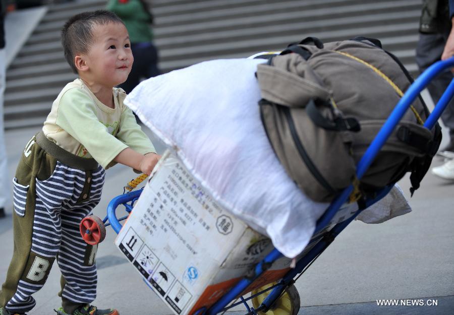 A little boy helps his family push the luggage case at Nanning train station in Nanning, capital of south China's Guangxi Zhuang Autonomous Region, Feb. 3, 2013. Many children travel with their families during the 40-day Spring Festival travel rush which started on Jan. 26. The Spring Festival, which falls on Feb. 10 this year, is traditionally the most important holiday of the Chinese people. Public transportation is expected to accommodate about 3.41 billion trips nationwide during the holiday, including 225 million trips by railways. (Photo/Xinhua)