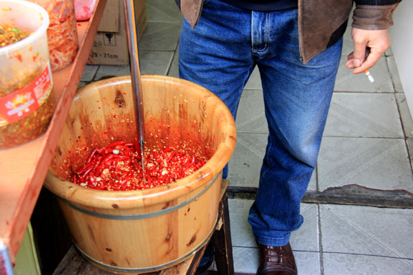 A man's cigarette dangles as he prepares a traditional chili sauce. (CRIENGLISH.com/William Wang)
