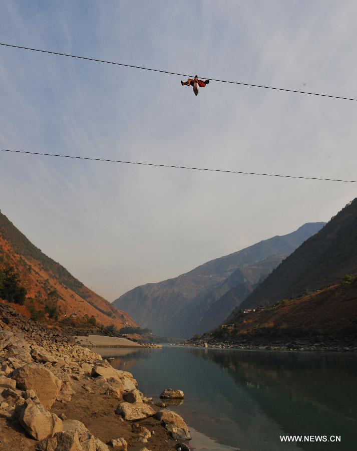 A resident from Shuangmidi Village crosses the Nujiang River via a zip-line in Liuku County of Nujiang Lisu Autonomous Prefecture, southwest China's Yunnan Province, Feb. 2, 2013. More than 98 percent of Nujiang Lisu Autonomous Prefecture is occupied by mountains and valleys. The zip-lines have been quite popular transportation method along the Nujiang River since the ancient time. However, as transport conditions improve in recent years, a growing number of traditional zip-lines along the Nujiang River Valley have been dismantled or replaced by bridges. (Xinhua/Wang Changshan)