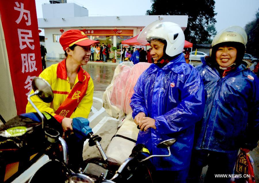 Chen Xianfu (C) and his wife (R), who are migrant workers from east China's Jiangxi Province, receive free refuelling service at a gas station before a homebound motorcycle journey starts in Fuzhou, capital of southeast China's Fujian Province, Feb. 5, 2013. Many migrant workers in China choose motorcycle as the means of transport when they return to their hometowns for family reunion during the Spring Festival. (Xinhua/Zhang Guojun) 