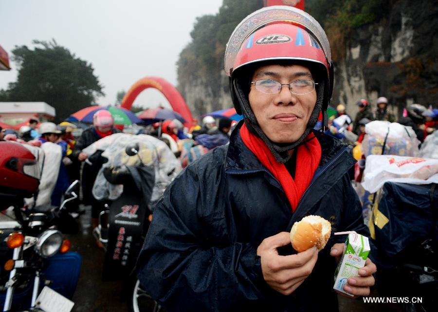 Chen Xinbao, a migrant worker from east China's Jiangxi Province, enjoys free breakfast at a gas station before a homebound motorcycle journey starts in Fuzhou, capital of southeast China's Fujian Province, Feb. 5, 2013. Many migrant workers in China choose motorcycle as the means of transport when they return to their hometowns for family reunion during the Spring Festival. (Xinhua/Zhang Guojun) 