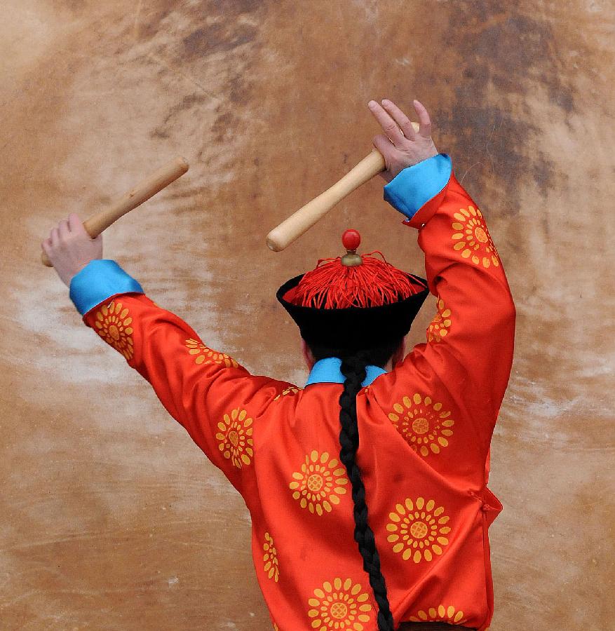 A performer dressed in costumes of the Qing Dynasty (1644-1911) beats the drum during a rehearsal of a performance presenting the ancient royal ritual to worship heaven at the Temple of Heaven in Beijing, capital of China, Feb. 5, 2013. (Xinhua/He Junchang) 