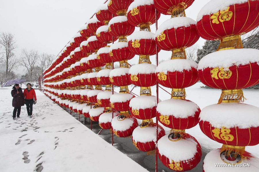 Visitors walk past lanterns covered with snow at a park in Lianyungang City, east China's Jiangsu Province, Feb. 5, 2013. (Xinhua/Wang Jianmin) 