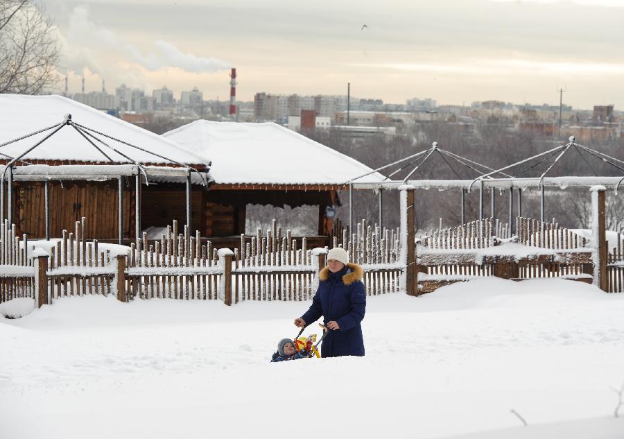 A woman walks with her kid in a park in Moscow, capital of Russia, on Feb. 5, 2013. A heavy snowfall hit Moscow on Sunday. (Xinhua/Jiang Kehong)