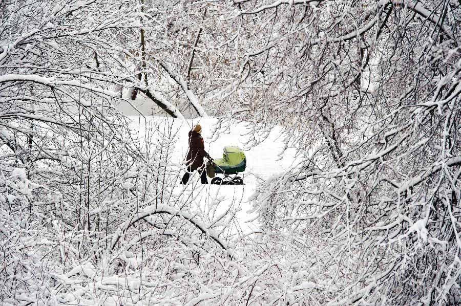 A woman walks in a park with her kid in Moscow, capital of Russia, on Feb. 5, 2013. A heavy snowfall hit Moscow on Sunday. (Xinhua/Jiang Kehong)