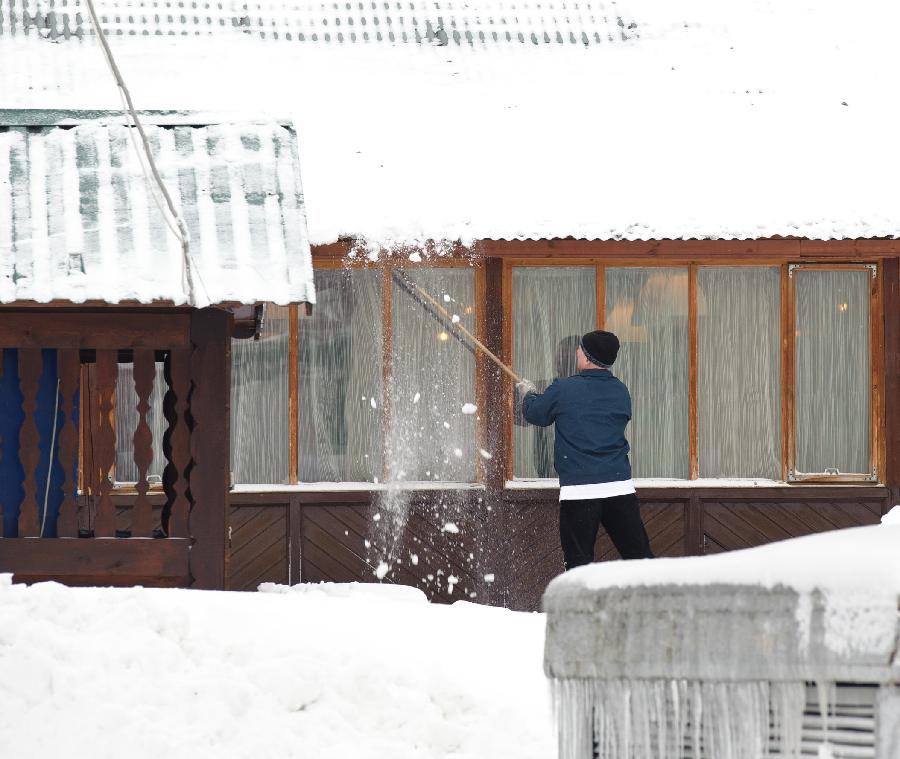 A man cleans snow from the roof of his house in Moscow, capital of Russia, on Feb. 5, 2013. A heavy snowfall hit Moscow on Sunday. (Xinhua/Jiang Kehong)