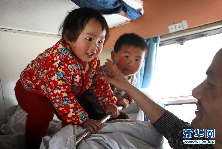 Yao Jingjing plays with his father in the hard sleeper carriage of a train to Fuyang city of Anhui on Jan. 30, 2013. (Xinhua/Pei Xin)