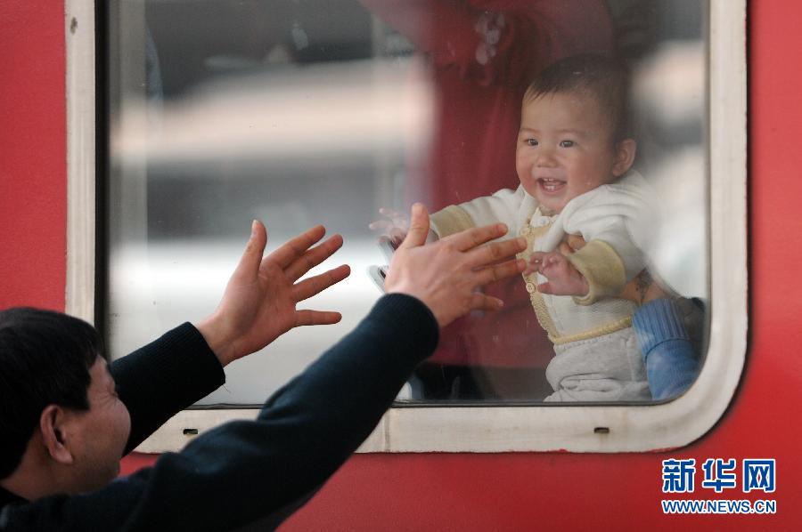 Yang plays with his grandson from the other side of the train window during the short station break of the journey from Ningbo to Guangzhou on Jan. 26, 2013. (Xinhua/Ju Huanzong)