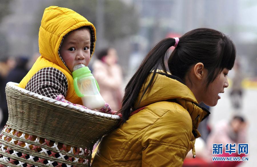 A child in a bamboo baskets on her mother's back at Chongqing Railway Station on Jan. 29, 2013. (Xinhua/Zhong Guilin)