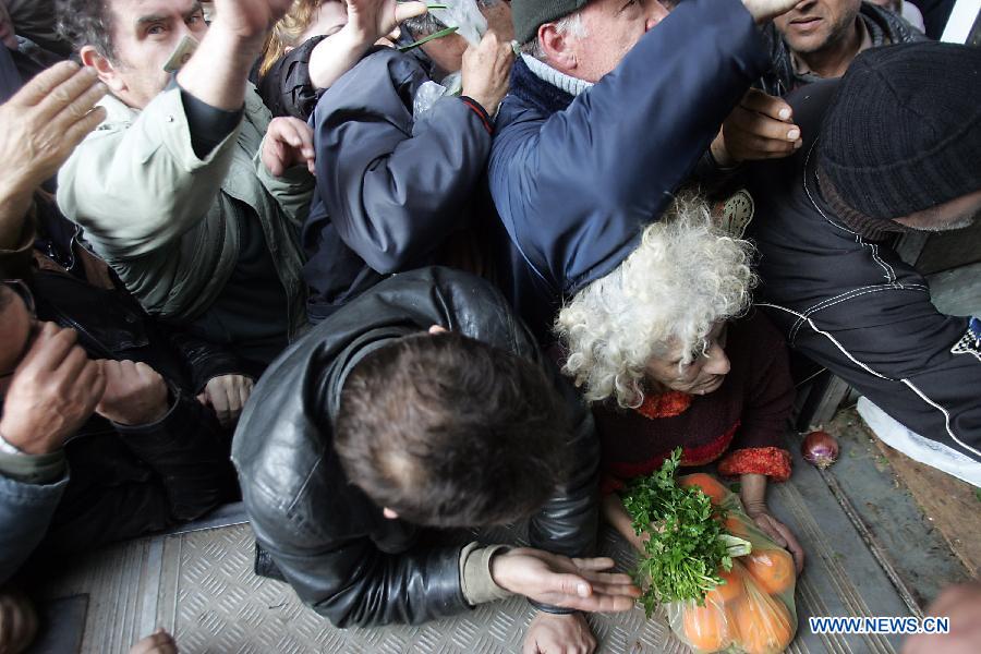 People reach out for free vegetables and fruits from farmers outside Greece's Agriculture Ministry in Athens, Greece, on Feb 6, 2013. Greek farmers continued on Wednesday their 10-day protests against tax hikes while distributing tons of vegetables and fruits for free to needy citizens. (Xinhua/Marios Lolos)