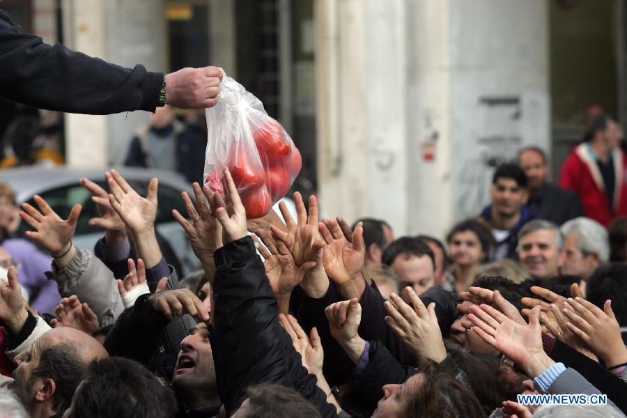 People reach out for free vegetables from farmers outside Greece's Agriculture Ministry in Athens, Greece, on Feb 6, 2013. Greek farmers continued on Wednesday their 10-day protests against tax hikes while distributing tons of vegetables and fruits for free to needy citizens. (Xinhua/Marios Lolos)