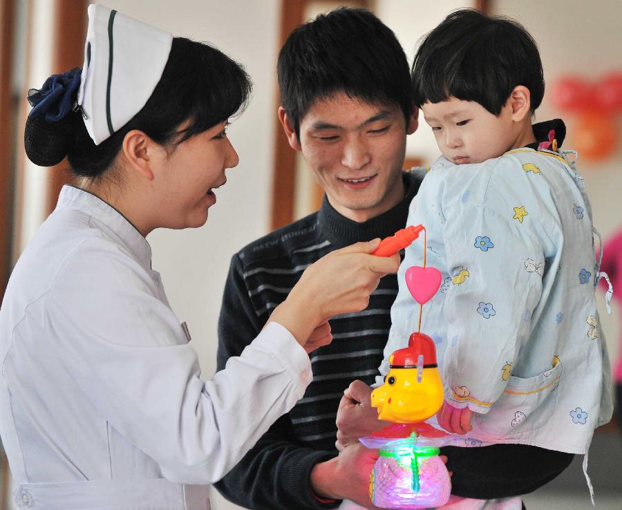 TIANJIN, Feb. 6, 2013 (Xinhua) -- A staff member (L) of Tianjin Medical University Cancer Institute and Hospital gives a lantern to a little patient at the hospital in north Tianjin's Municipality, Feb. 6, 2013. A Spring Festival party is held at the hospital on Wednesday for children receiving treatment and not returning home during the festival. The 2013 Spring Festival, which falls on Feb. 10, is traditionally the most important holiday of the Chinese people. (Xinhua/Yue Yuewei)