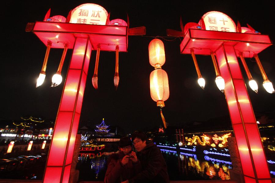Visitors look at photos during the 2013 Nanjing Qinhuai Lantern Show at the Confucius Temple in Nanjing, capital of east China's Jiangsu Province, Feb. 6, 2013. Around 500,000 lanterns are displayed during the event to celebrated the upcoming Spring Festival which falls on Feb. 10 this year. (Xinhua/Dong Jinlin) 
