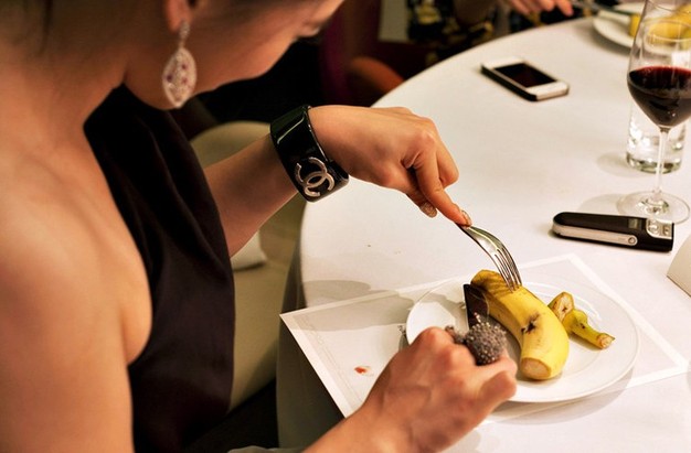 Ladies learn how to use fork and knife to cut banana. (Photo/Xinhua) 