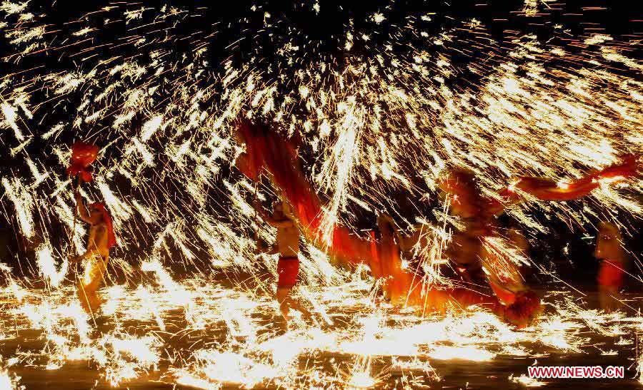 Actors perform dragon dance in firecrackers at the Daguan Park in Kunming, capital of southwest China's Yunnan Province, Feb. 6, 2013. The dance, as a derivative of traditional dragon dance in which performers hold dragon on poles and walk through floods of firecrackers, is a state intangible cultural heritage. (Xinhua/Lin Yiguang)
