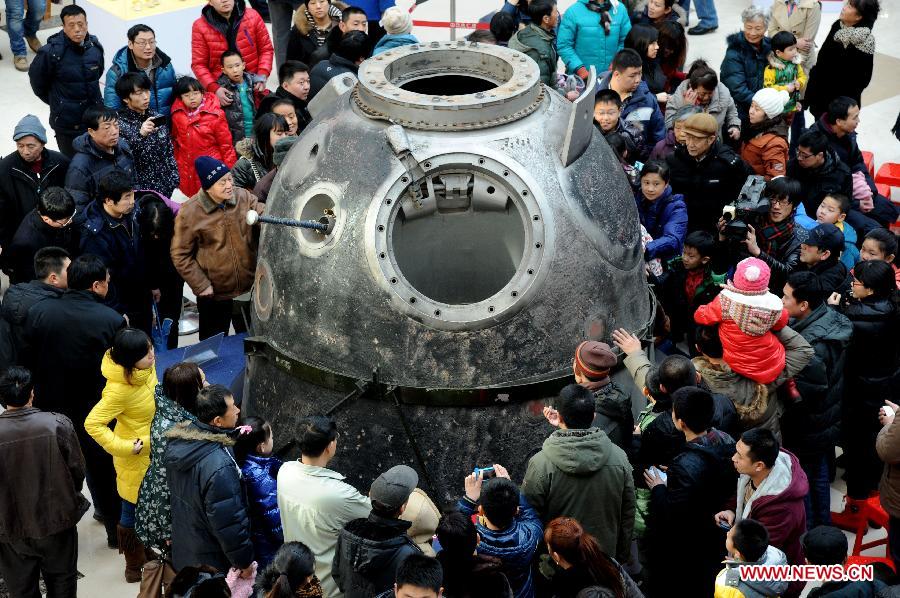 Visitors look at a return capsule of Shenzhou spacecraft presented on the First Shenyang Aerospace Science Exhibition in Shenyang, capital of northeast China's Liaoning Province, Feb. 7, 2013. Space food, devices, models of Shenzhou spacecraft and China-developped rockets are among the exhibits. (Xinhua/Zhang Wenkui)