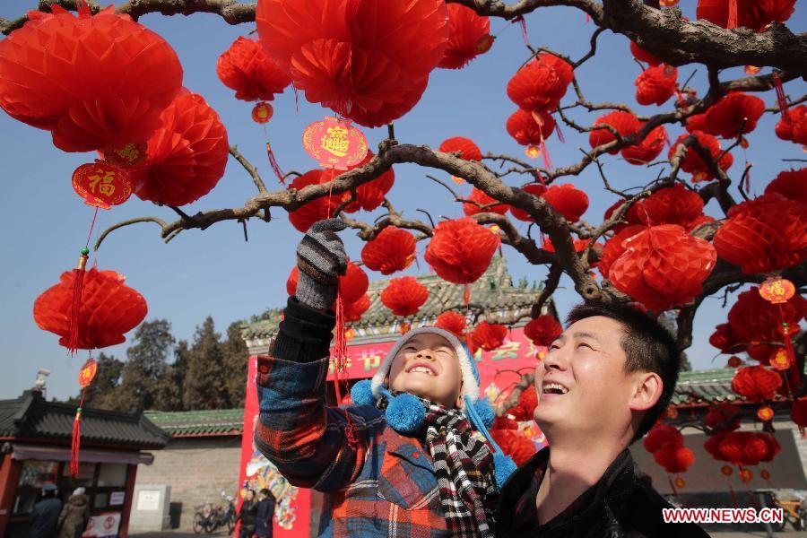 People look at red lanterns hung on a tree outside the south gate of Ditan Park in Beijing, capital of China, Feb. 8, 2013. The Spring Festival, the most important occasion for the family reunion for the Chinese people, falls on the first day of the first month of the traditional Chinese lunar calendar, or Feb. 10 this year. (Xinhua/Chen Xiaogen)