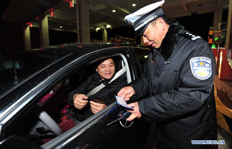 A policeman checks a driving license in Fuzhou, capital of capital of southeast China's Fujian Province, Feb. 9, 2013. The highways in China will be toll-free for passenger cars from 0:00 on Feb. 9 to 24:00 on Feb. 15 when most Chinese will go home for the Spring Festival and return to work. (Xinhua/Wei Peiquan)