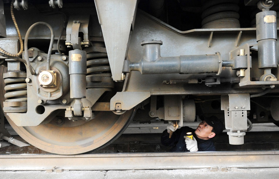 A railway worker inspects the braking system of a train that will be used in the Spring Festival travel season in Zhengzhou, Henan province, Feb. 2. (Xinhua/Li Bo)