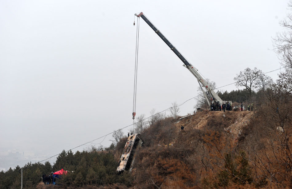 A burnt coach is lift from a ravine in Ning county, Gansu province, Feb. 2. An overloaded coach caught fire after falling into a ravine on Feb.1, killing 18 and injuring 32. (Photo/Xinhua)