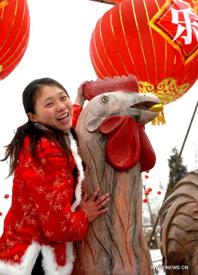 File photo taken on Feb. 9, 2005 shows a woman posing for a photo with a stone sculpture of rooster at a temple fair in Zhengzhou, capital of central China's Henan Province. 2005 was the Year of the Rooster in the Chinese Zodiac. Chinese Zodiac is represented by 12 animals to record the years and reflect people's attributes, including the rat, ox, tiger, rabbit, dragon, snake, horse, sheep, monkey, rooster, dog and pig.(Xinhua/Wang Song) 