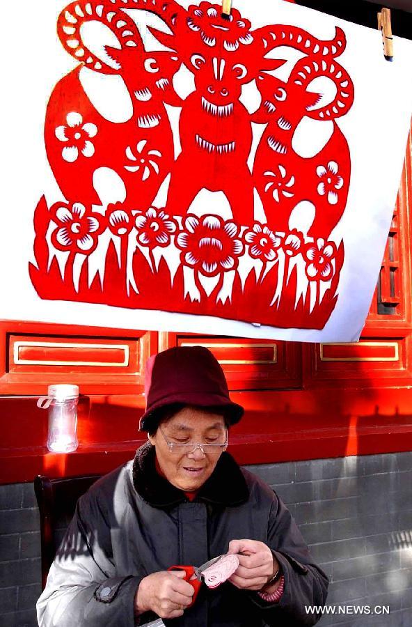 File photo taken on Feb. 6, 2003 shows a folk artist making a papercutting of sheep in a temple fair in Zhengzhou, capital of central China's Henan Province. 2003 was the Year of the Sheep in the Chinese Zodiac. Chinese Zodiac is represented by 12 animals to record the years and reflect people's attributes, including the rat, ox, tiger, rabbit, dragon, snake, horse, sheep, monkey, rooster, dog and pig.(Xinhua/Wang Song)