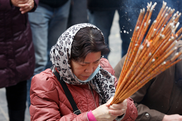 A woman burns incense as she pray for good fortune on the first day of the Chinese Lunar New Year at Yonghegong Lama Temple in Beijing Feb 10, 2013. (Photo/chinadaily.com.cn)