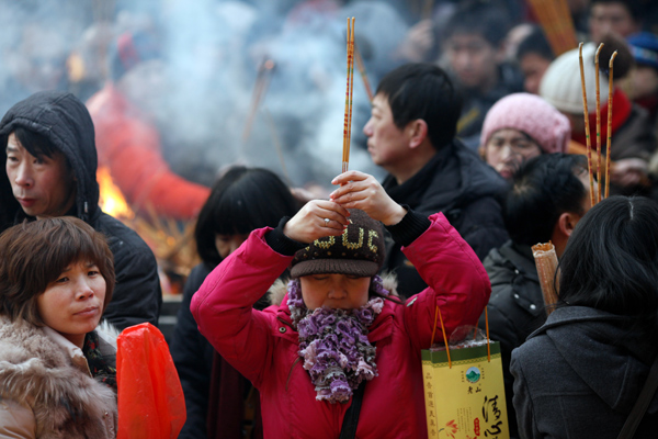 People pray for good fortune as they hold burning incense on the first day of the Chinese Lunar New Year at Yonghegong Lama Temple in Beijing Feb 10, 2013. The Lunar New Year, or Spring Festival, begins on Feb 10 and marks the start of the Year of the Snake, according to the Chinese zodiac. (Photo/chinadaily.com.cn)