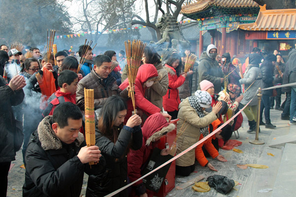 People pray for good fortune as they hold burning incense on the first day of the Chinese Lunar New Year at Yonghegong Lama Temple in Beijing Feb 10, 2013. (Photo/chinadaily.com.cn)