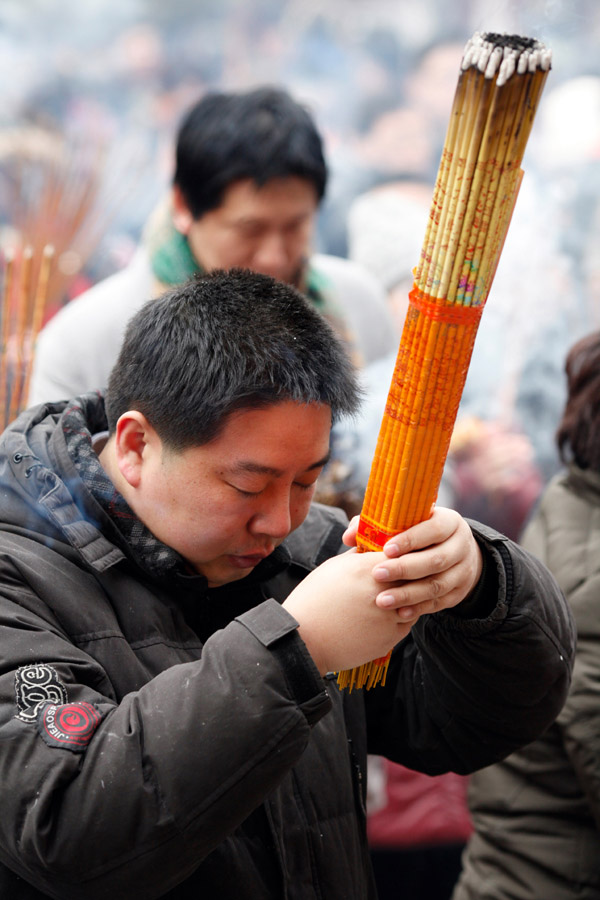 A man burns incense to pray for good fortune on the first day of the Chinese Lunar New Year at Yonghegong Lama Temple, in Beijing Feb 10, 2013. (Photo/chinadaily.com.cn)