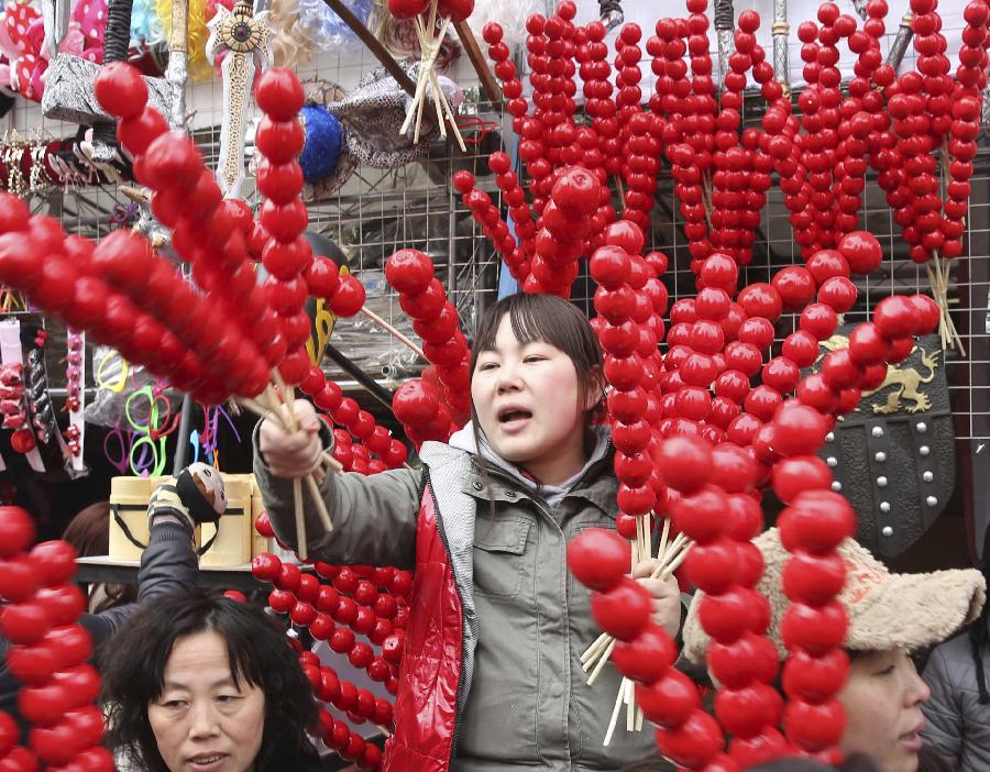 A vendor cries her sugar-coated haws at a templ fair held to celebrate Chinese Lunar New Year, or Spring Festival, in the Ditan Park, Beijing, capital of China, Feb. 10, 2013. Various activities were held all over China on Sunday to celebrate the Spring Festival, marking the start of Chinese lunar Year of the snake. The Spring Festival falls on Feb. 10 this year. (Xinhua/Liang Zhiqiang) 