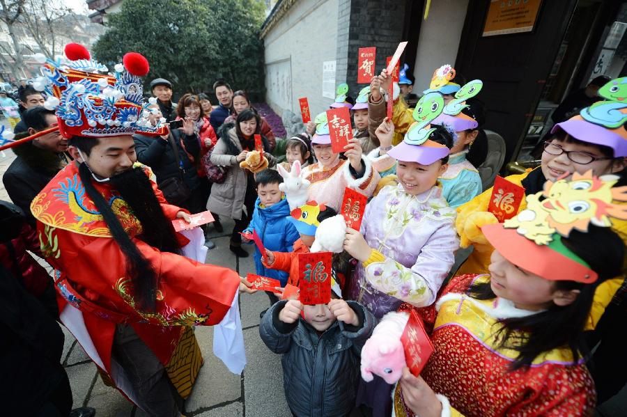 A staff member of the Heyuan Garden dressed as the God of Wealth distributes red packets to children at a local event celebrating Chinese Lunar New Year, or Spring Festival, at the Heyuan Garden, Yangzhou City, east China's Jiangsu Province, Feb. 10, 2013. Various activities were held all over China on Sunday to celebrate the Spring Festival, marking the start of Chinese lunar Year of the snake. The Spring Festival falls on Feb. 10 this year. (Xinhua/Meng Delong) 