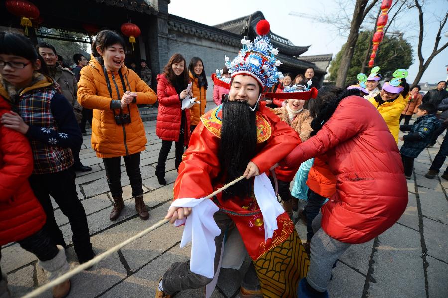 A staff member of the Heyuan Garden dressed as the God of Wealth participates in tug of war with tourists at a local event celebrating Chinese Lunar New Year, or Spring Festival, at the Heyuan Garden, Yangzhou City, east China's Jiangsu Province, Feb. 10, 2013. Various activities were held all over China on Sunday to celebrate the Spring Festival, marking the start of Chinese lunar Year of the snake. The Spring Festival falls on Feb. 10 this year. (Xinhua/Meng Delong) 