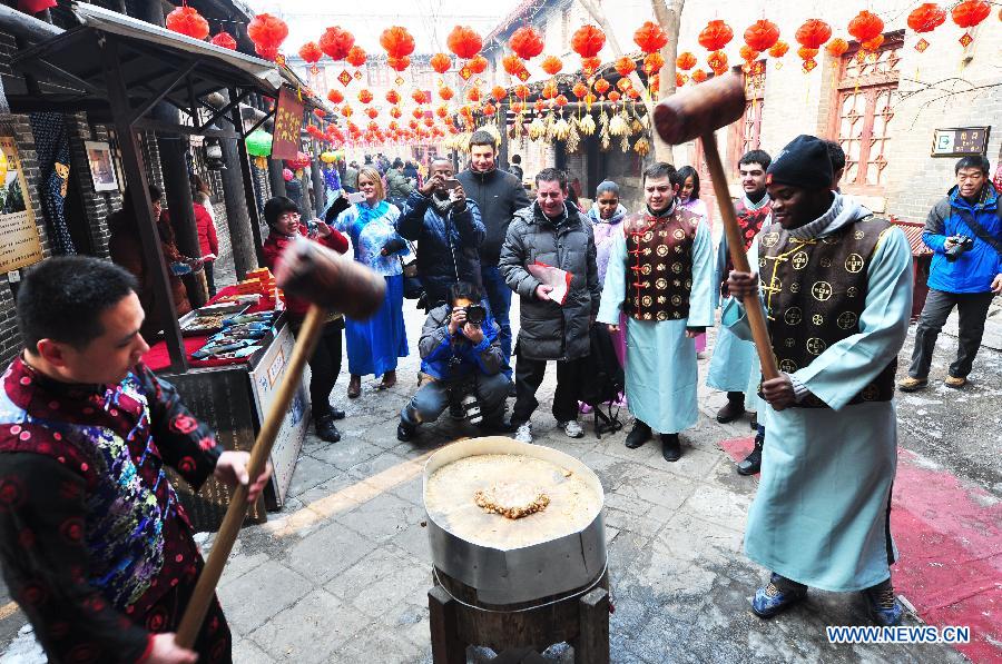 A foreign student (R) learns to make "Tang Gao", or sugar cake, during his visit to Zhoucun District of Zibo City, east China's Shandong Province, Feb. 10, 2013. Over 20 foreign students from different countries came to the ancient town on Sunday to celebrate the Spring Festival with local people. The Spring Festival falls on Feb. 10 this year. (Xinhua/Dong Naide) 