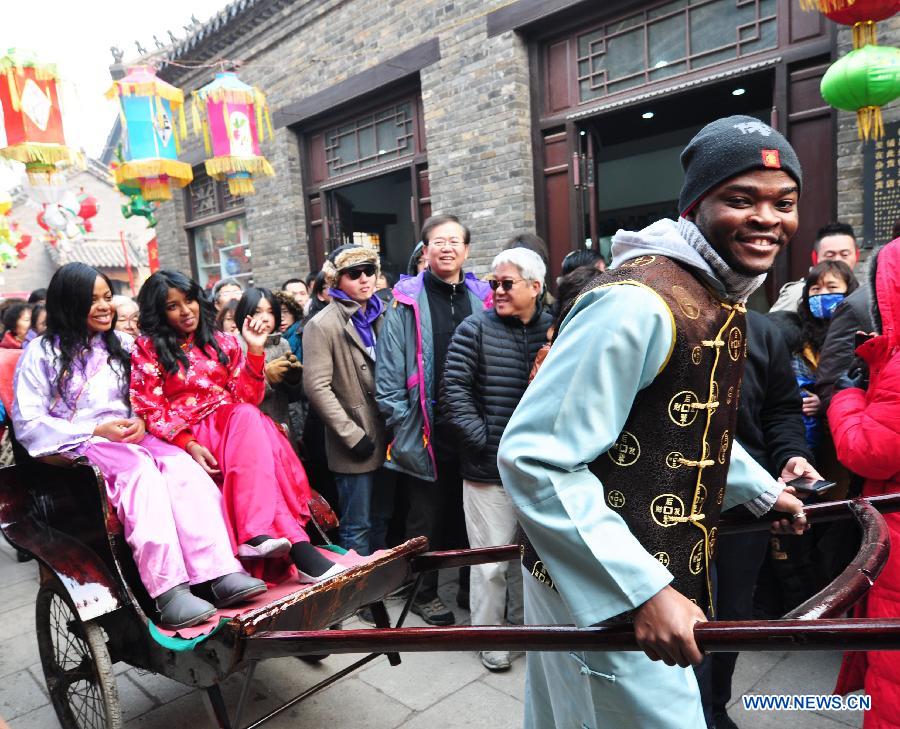 A foreign student carries his friends forward with a rickshaw during their visit to Zhoucun District of Zibo City, east China's Shandong Province, Feb. 10, 2013. Over 20 foreign students from different countries came to the ancient town on Sunday to celebrate the Spring Festival with local people. The Spring Festival falls on Feb. 10 this year. (Xinhua/Dong Naide)  