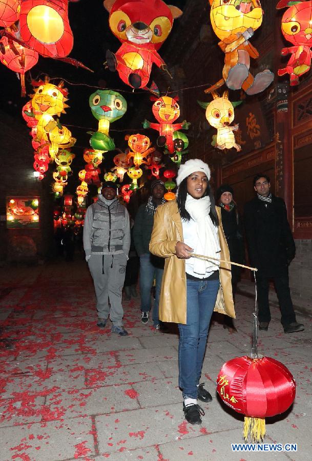 Foreign students walk in a street decorated with lanterns in the shape of Chinese Zodiac animals in Zhoucun District of Zibo City, east China's Shandong Province, Feb. 10, 2013. Over 20 foreign students from different countries came to the ancient town on Sunday to celebrate the Spring Festival with local people. The Spring Festival falls on Feb. 10 this year. (Xinhua/Dong Naide) 