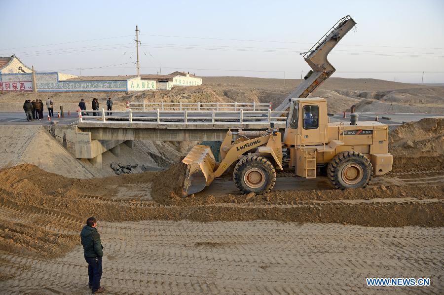 A bulldozer works to open an alternative pathway beside the crushed bridge on the No. 304 Provincial Highway, the Shuitao Village, Hongsibao District of Wuzhong City, northwest China's Ningxia Hui Autonomous Region, Feb. 10, 2013. According to local highway authorities, an overloaded truck carrying the outsized casting, with a gross weight of 100 tons, crushed the bridge with design load of only 55 tons when the truck tried to pass over it. (Xinhua/Wang Peng)