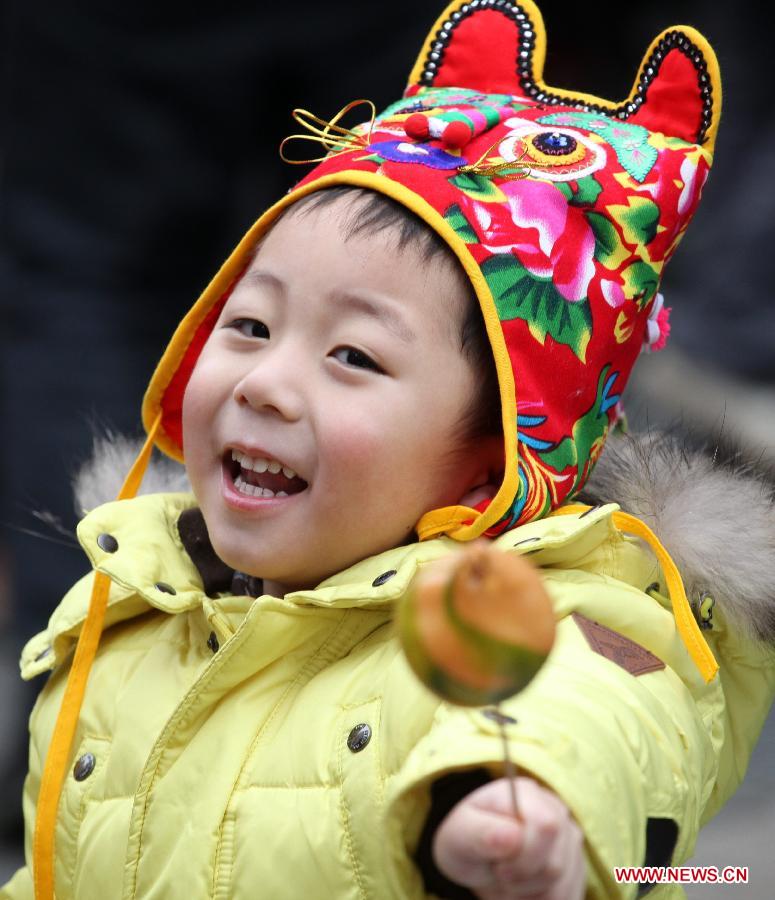 A child shows his sugar figurine at a temple fair in Nanjing, capital of east China's Jiangsu Province, Feb. 11, 2013. Temple fair, a Chinese cultural gathering traditionally adjacent to temples, is usually held around the time of the Chinese Lunar New Year. At the fair, activities include worshiping deities, entertainment and shopping. (Xinhua/Li Wenbao)
